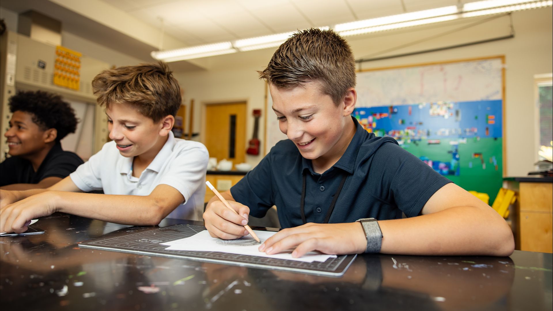 Students smiling and working together on a project in a classroom