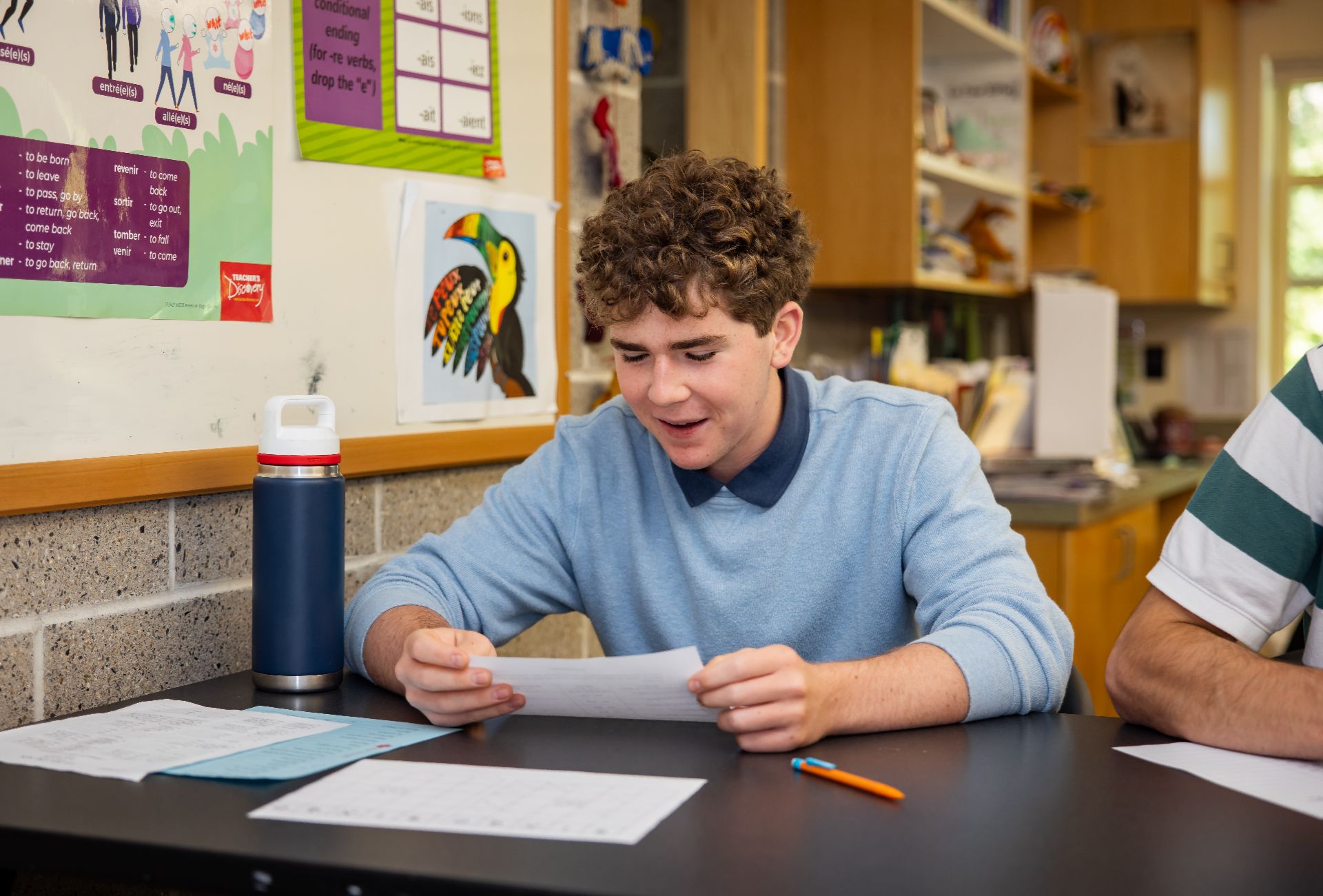 A curly-haired student reviewing notes at a classroom desk