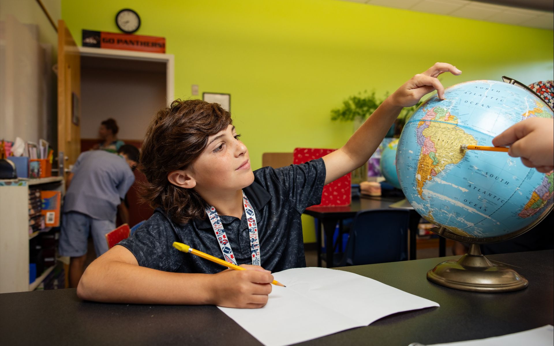 Student pointing to a world globe during a geography lesson