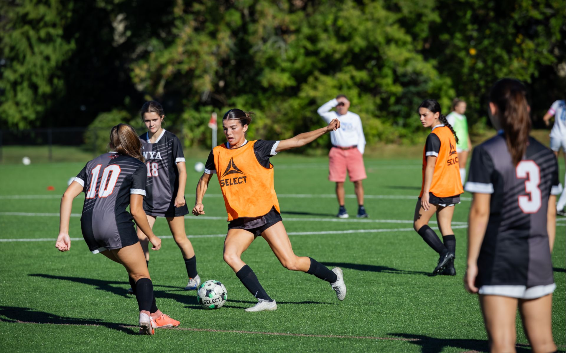 High school girls playing a soccer match on a sunny outdoor field