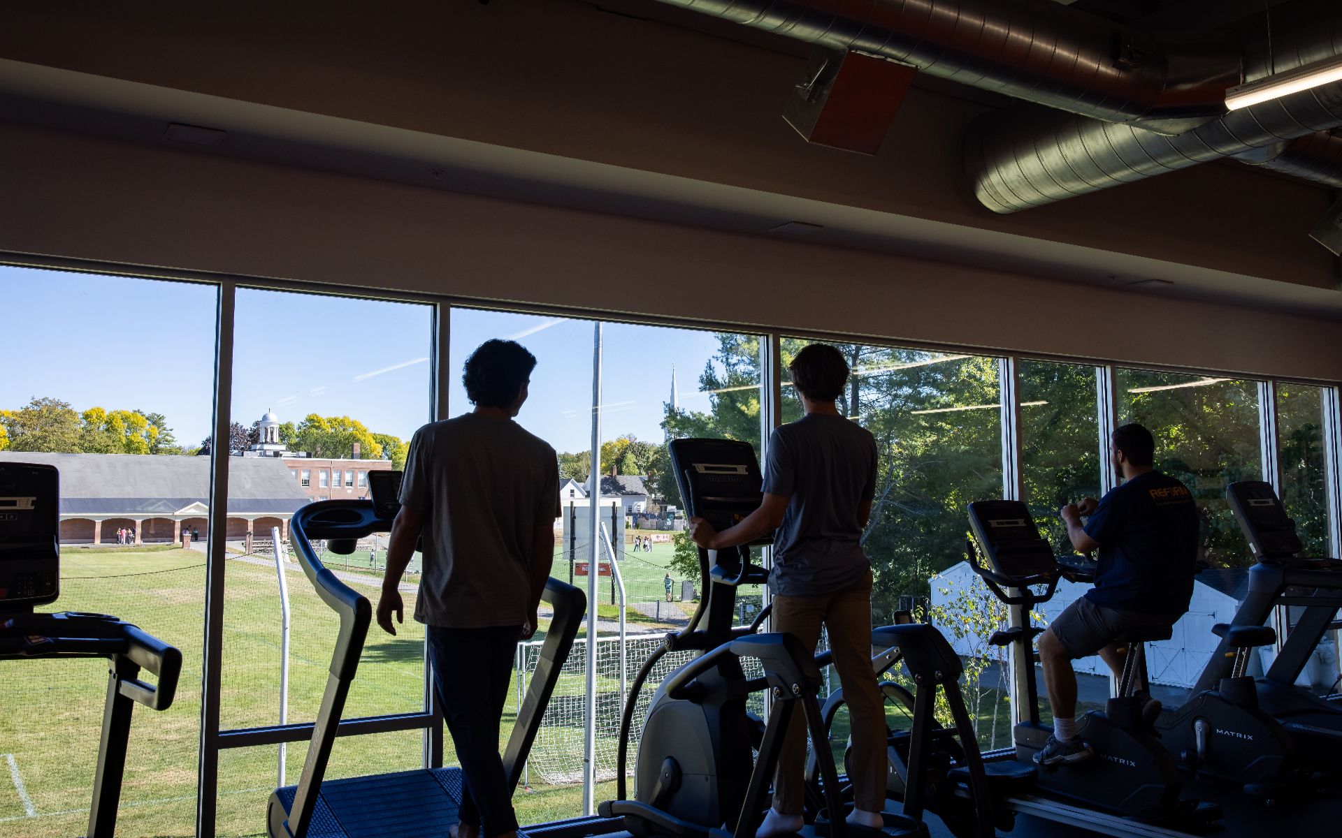 Students exercising on cardio equipment overlooking the school campus