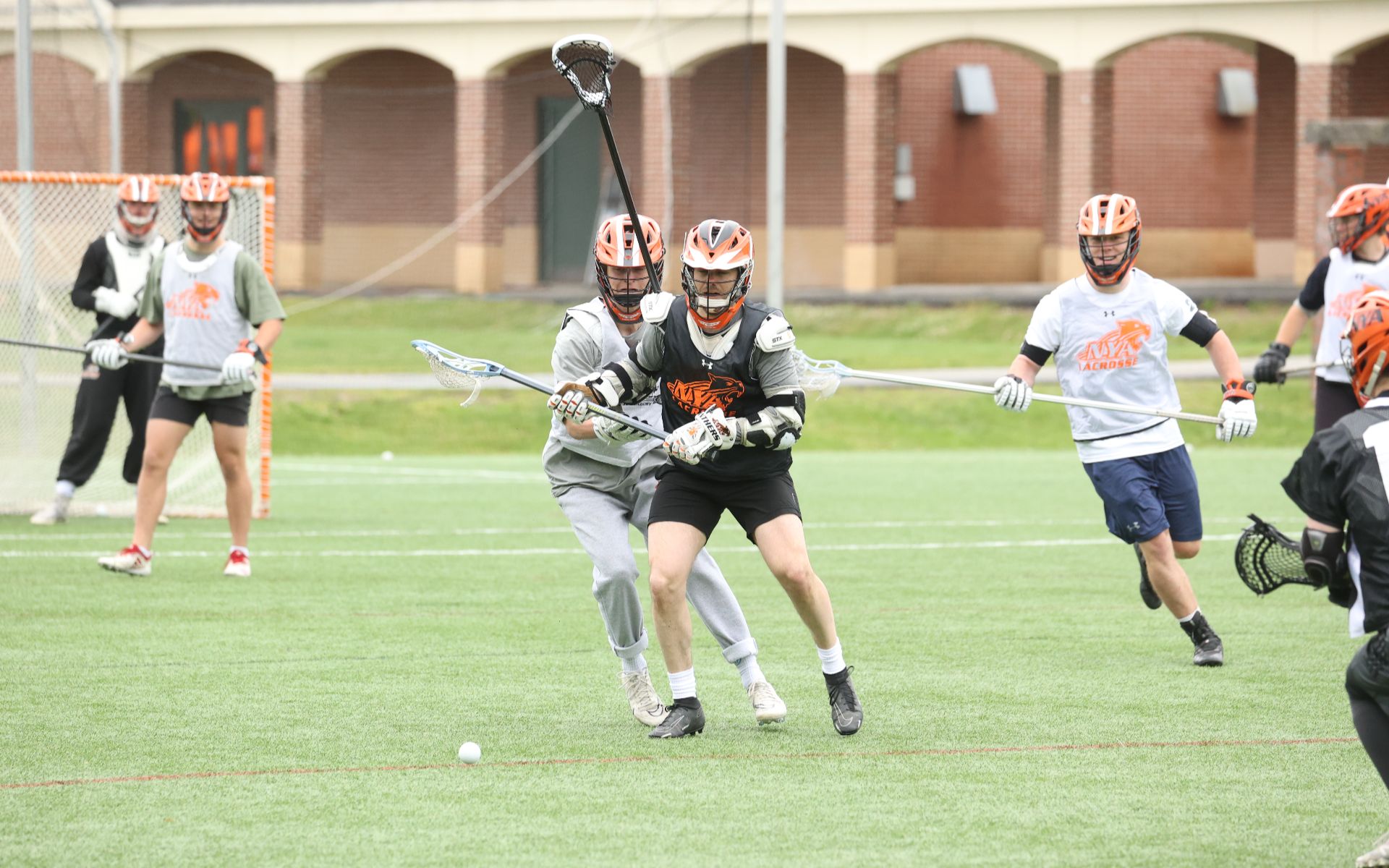 Students playing an intense lacrosse game on a school turf field