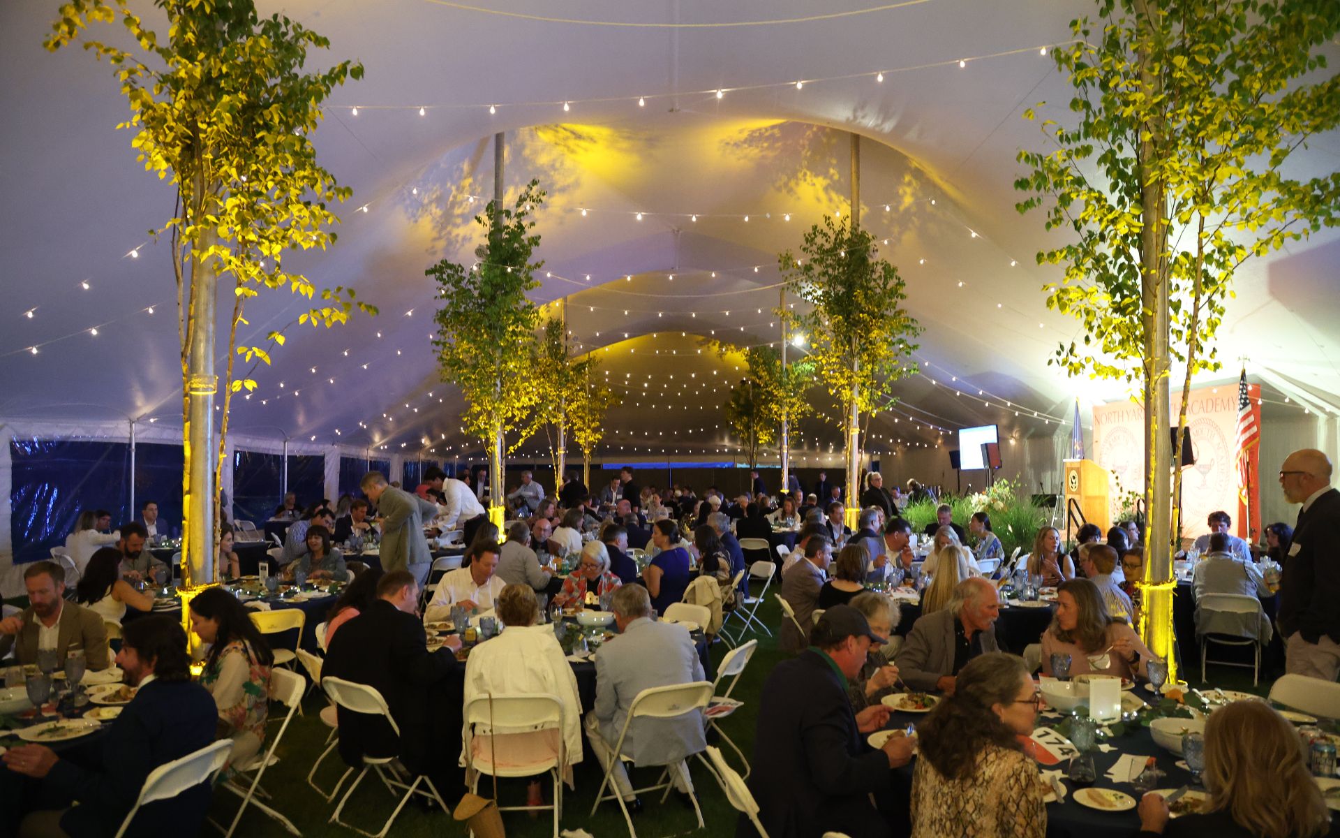 A formal dinner event inside a decorated tent